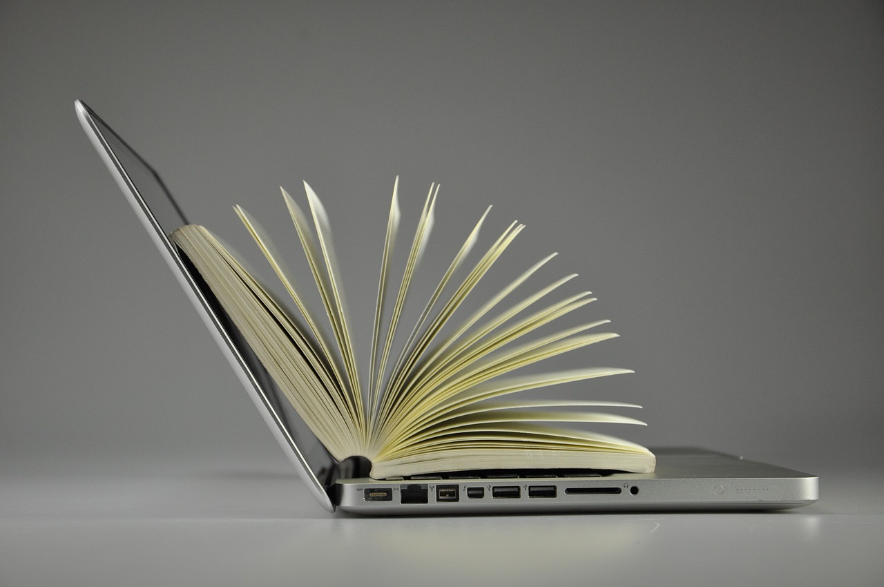 Side view of a laptop with book flared open on top